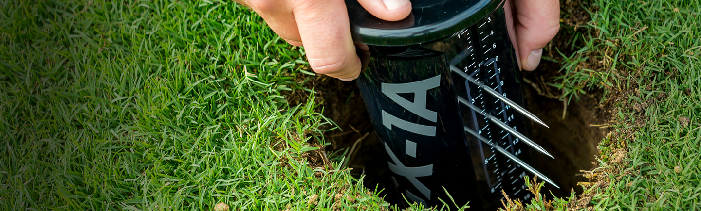 Person using a black soil sensor on grass